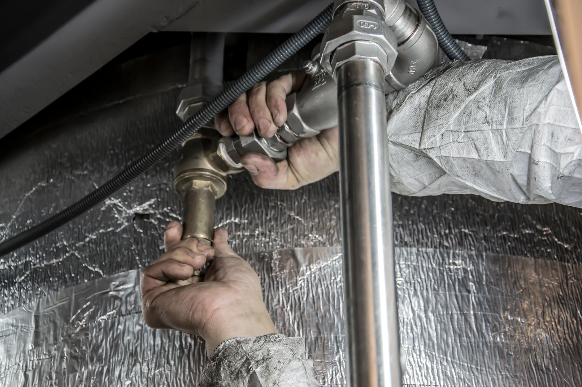Close-up of hands installing steel pipes indoors